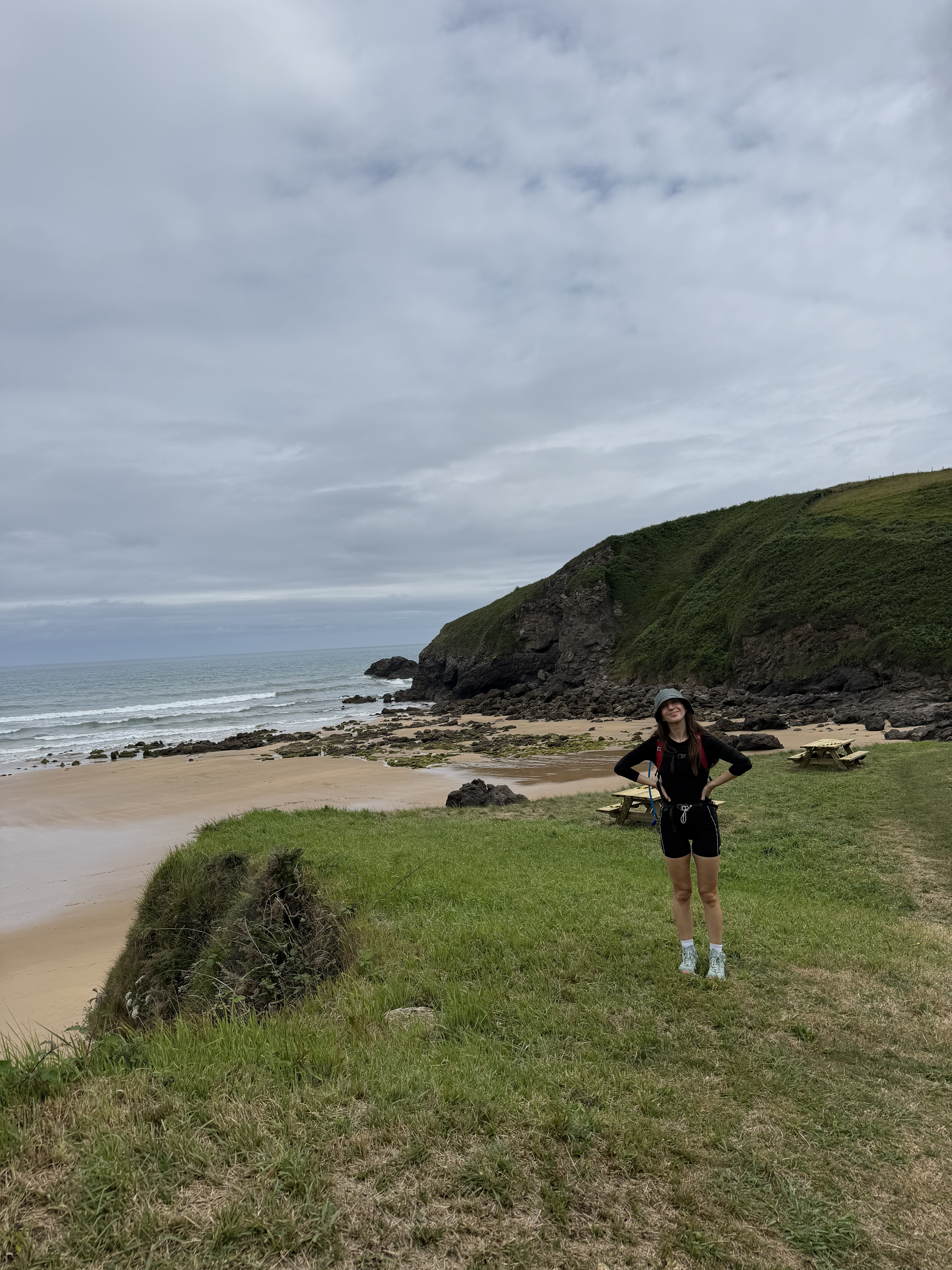 Ariana hiking beside a beach and grassy coastal cliffs
